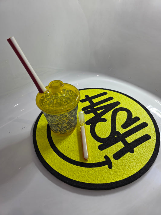 Slop Glass x Disk Glass Yellow glass rig cup with patterned base, red straw, and decorative lid on a reflective surface.