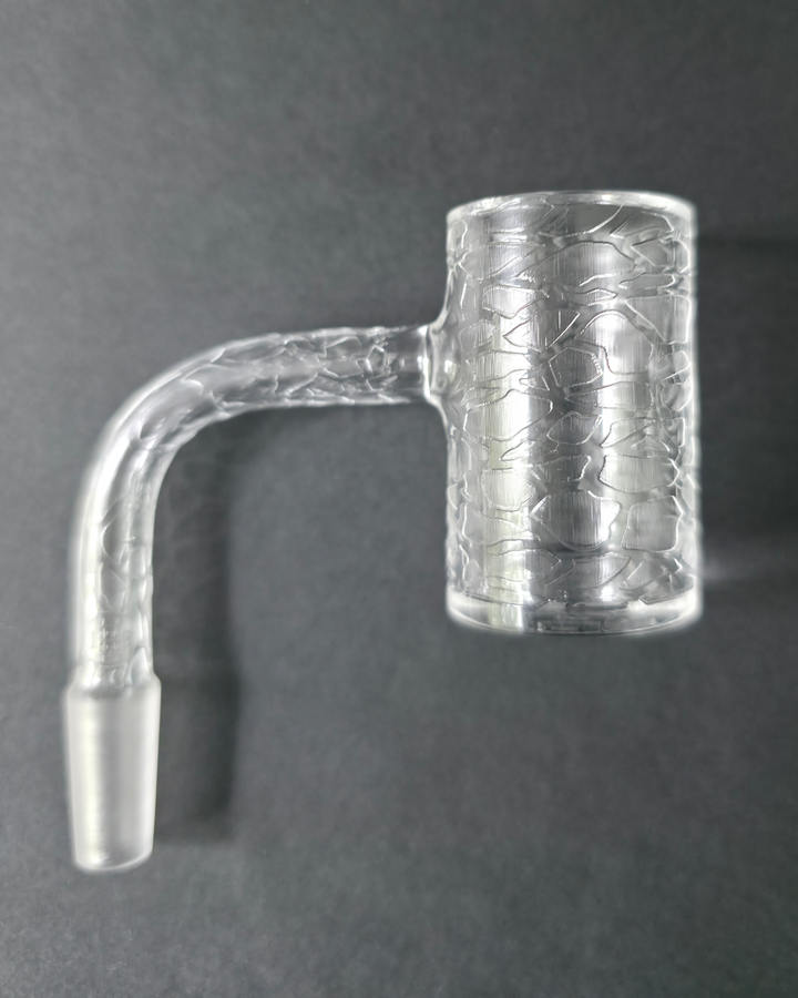 Clear glass quartz banger with embossed design on a dark grey background