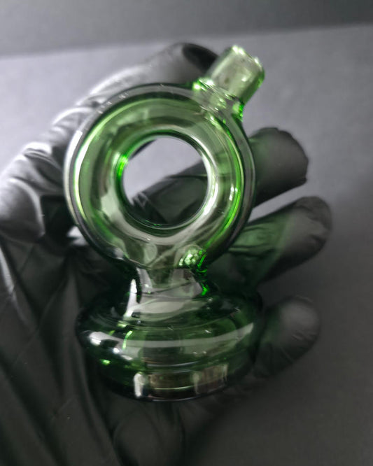 Green glass smoking accessory held by a gloved hand on a dark background