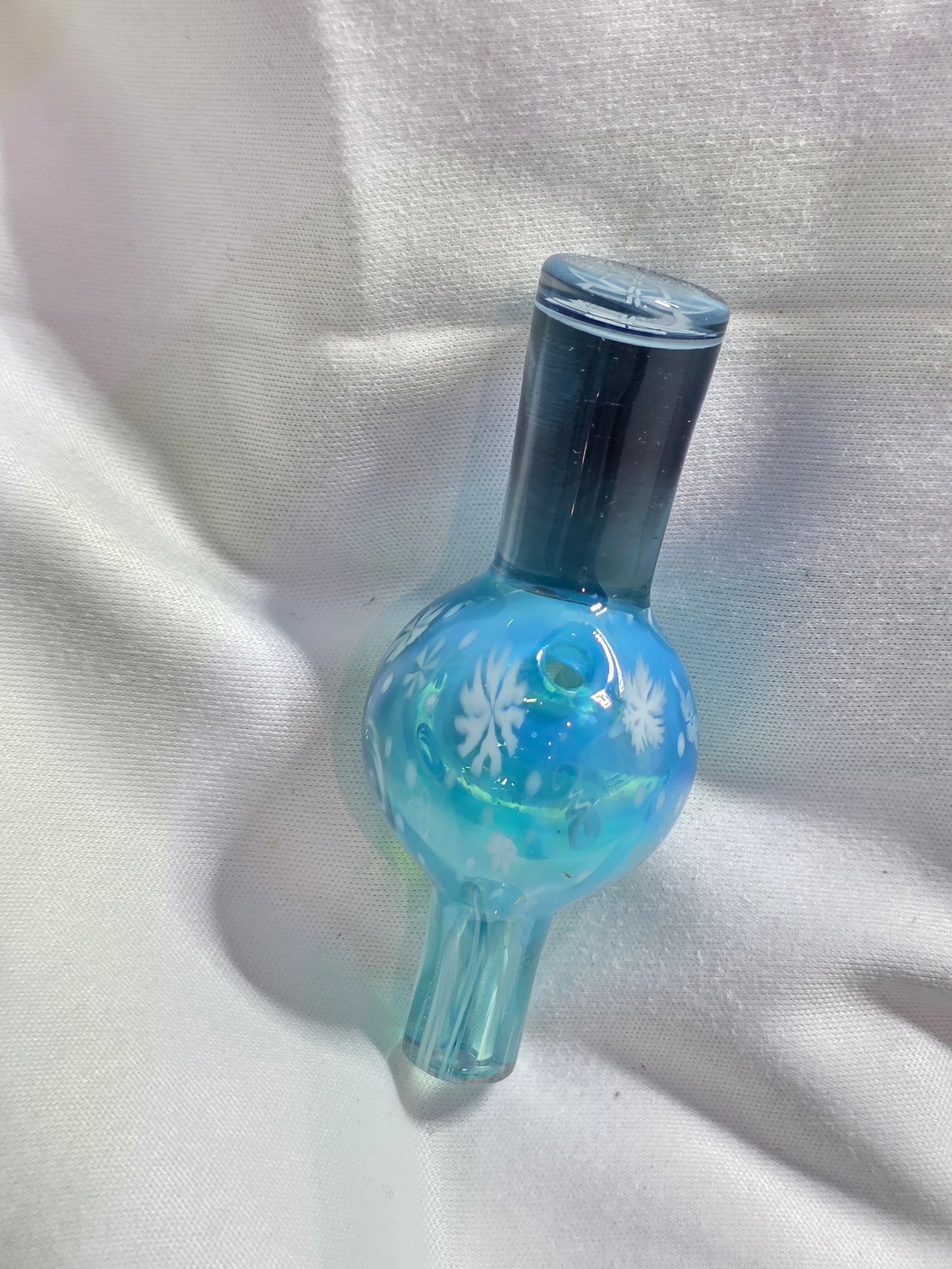 Glass smoking accessory with blue and clear design on a white fabric background