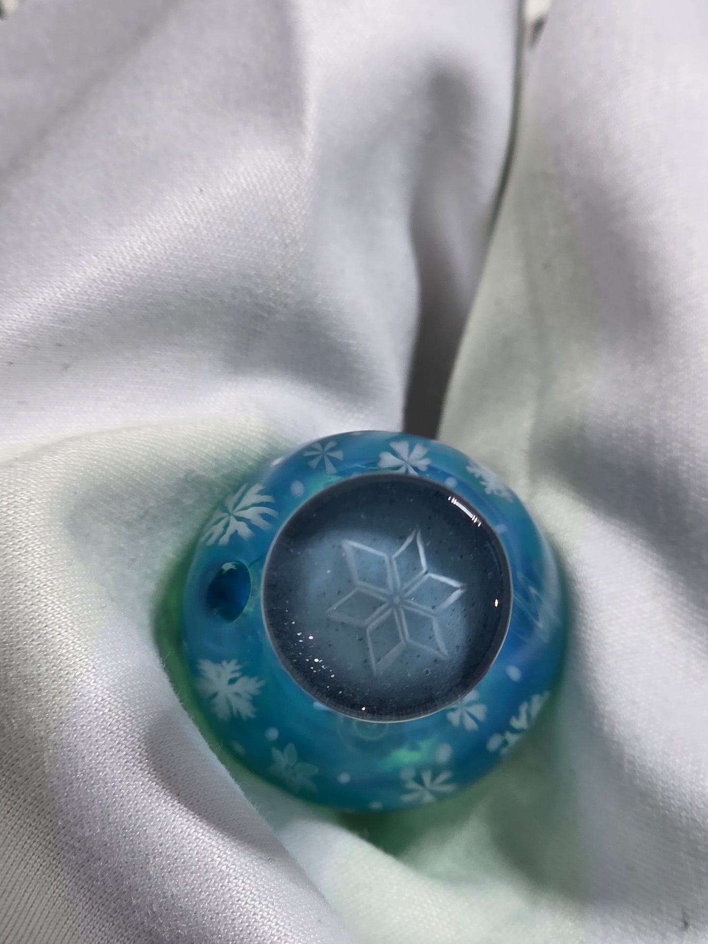 Blue glass marble with a star design on a white fabric background
