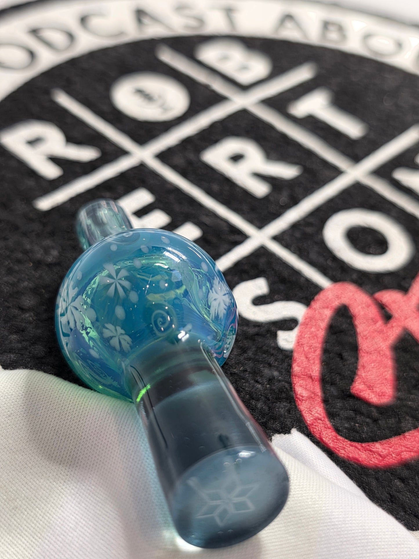 Blue glass top cap with floral design on a textured background