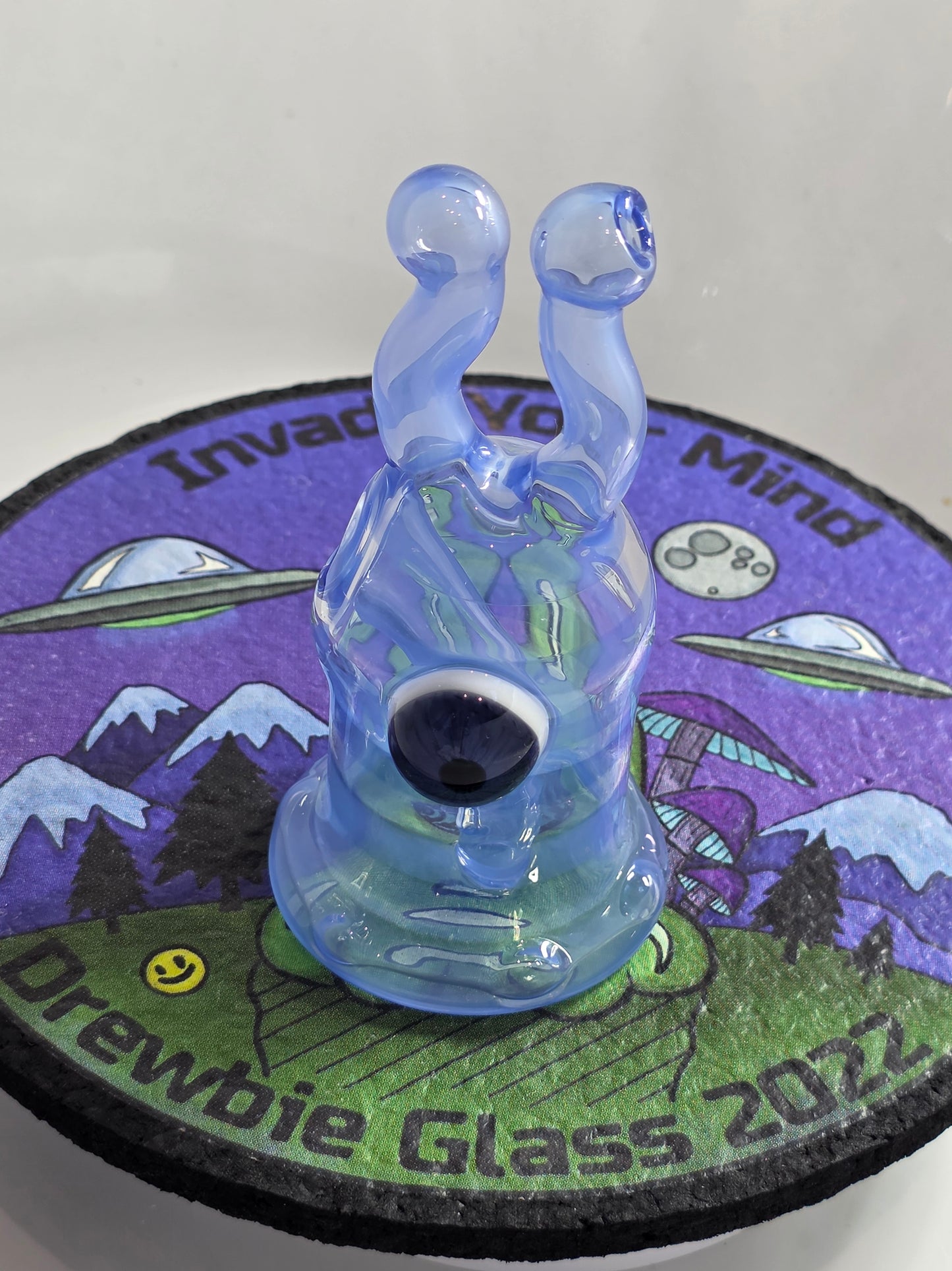 Drewbie Glass Glass Rig.Blue and white fish-shaped object with a prominent eye on a colourful background