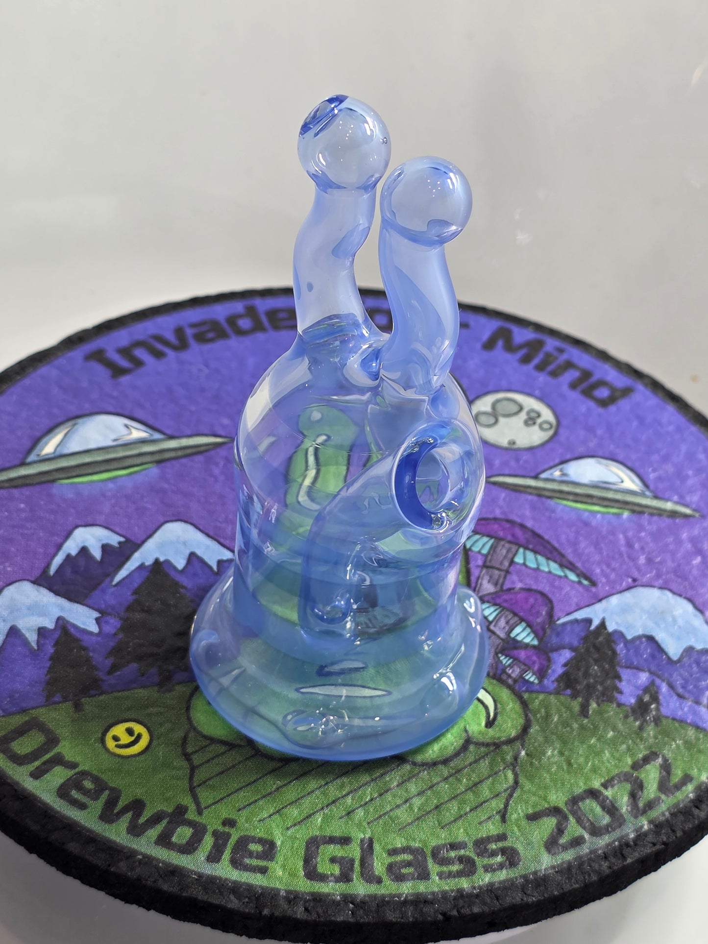 Drewbie Glass Glass Rig.Blue and white fish-shaped object with a prominent eye on a colourful background