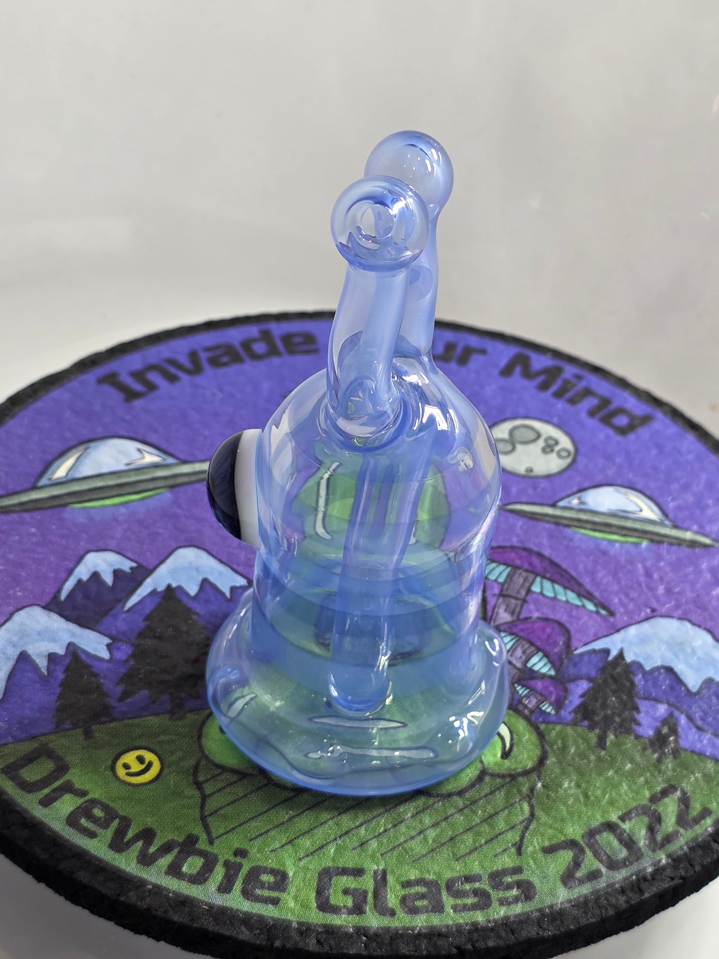 Drewbie Glass Glass Rig.Blue and white fish-shaped object with a prominent eye on a colorful background
