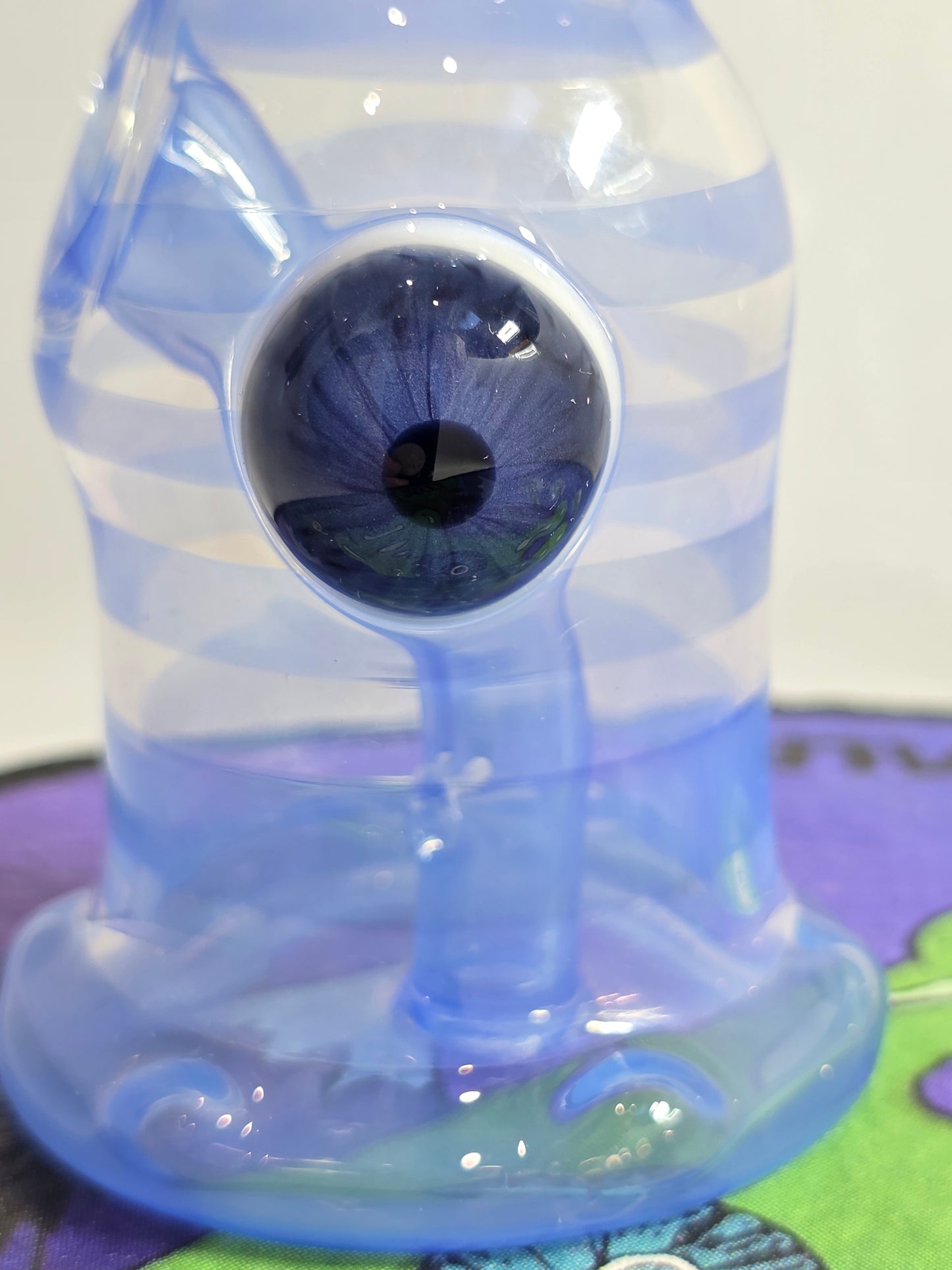 Drewbie Glass Glass Rig.Blue and white fish-shaped object with a prominent eye on a colorful background