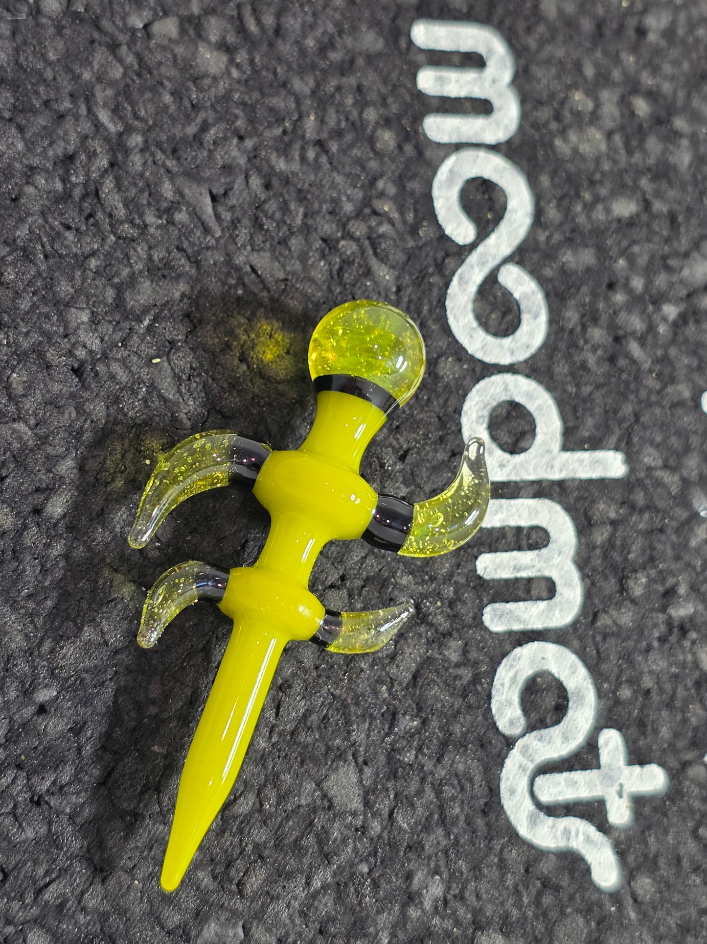 Yellow and clear top cap on a black surface with 'moodmats' branding.