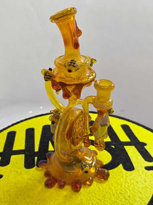 Joe P Glass Rig . A bee themed glass rig with bees and honey dripping on a white background and has a banger attached to it 