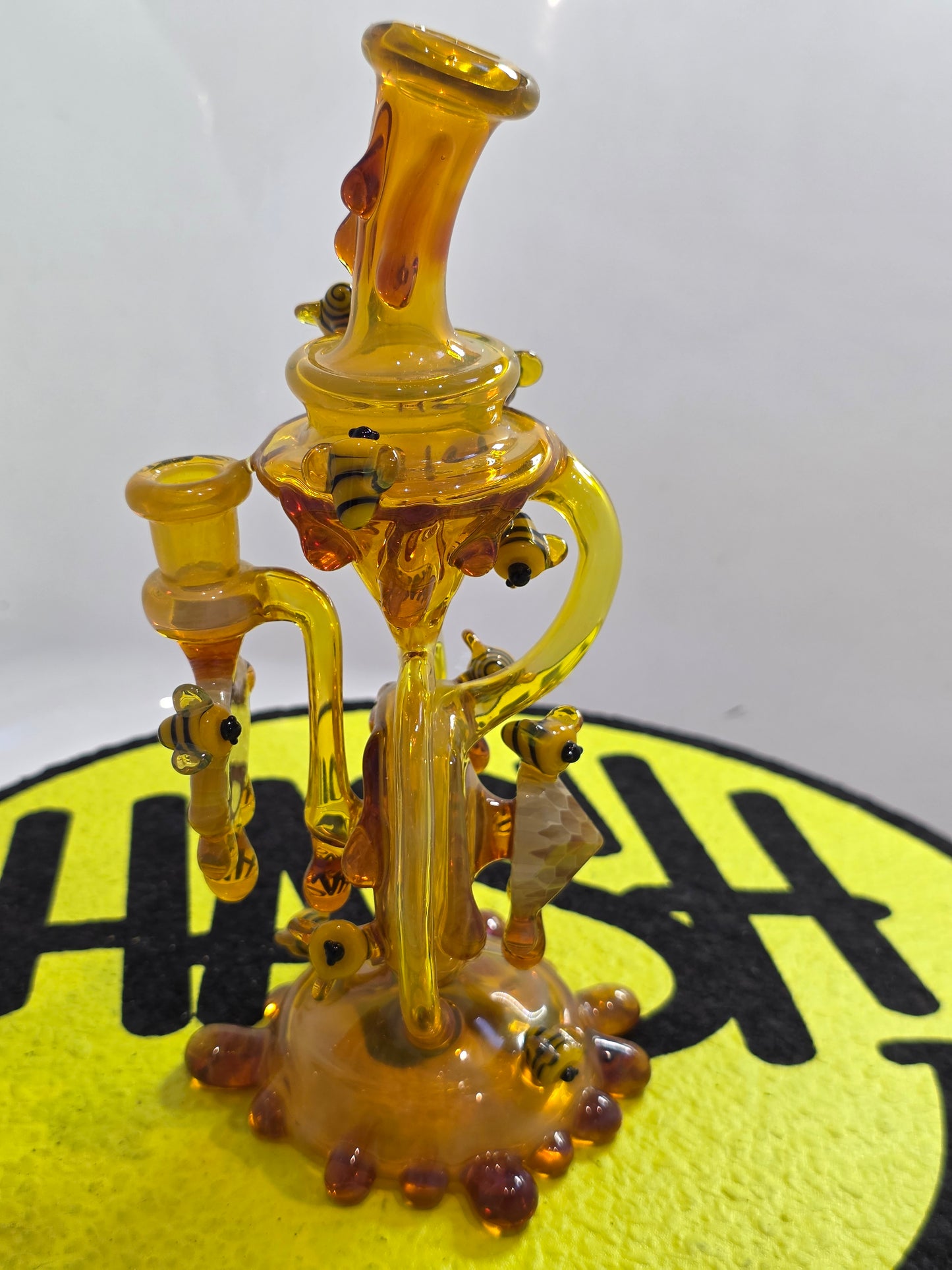 Joe P Glass Rig . A bee themed glass rig with bees and honey dripping on a white background and has a banger attached to it 