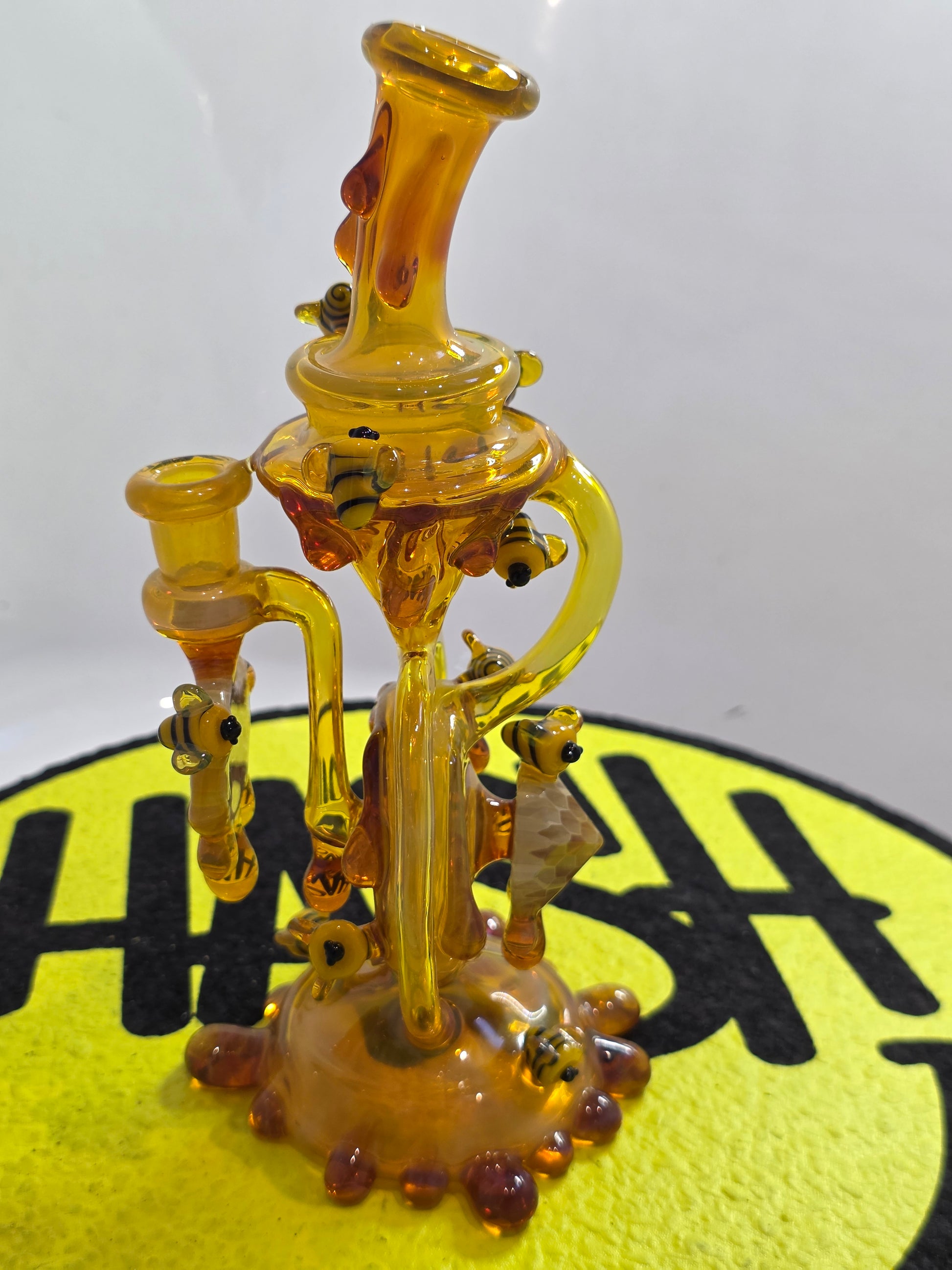 Joe P Glass Rig . A bee themed glass rig with bees and honey dripping on a white background and has a banger attached to it 