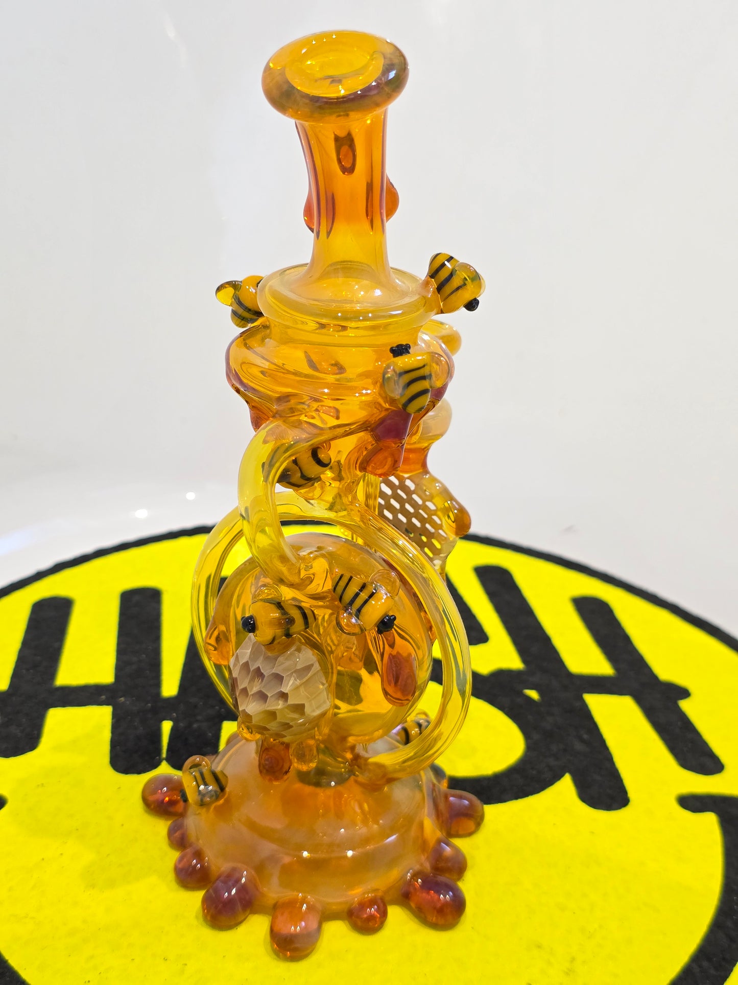 Joe P Glass Rig . A bee themed glass rig with bees and honey dripping on a white background and has a banger attached to it 