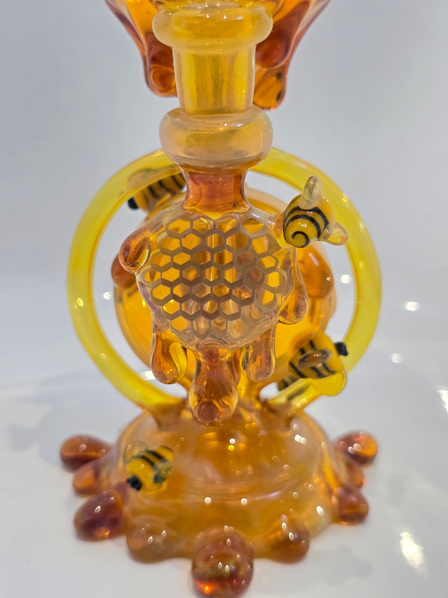 Joe P Glass Rig . A bee themed glass rig with bees and honey dripping on a white background and has a banger attached to it 
