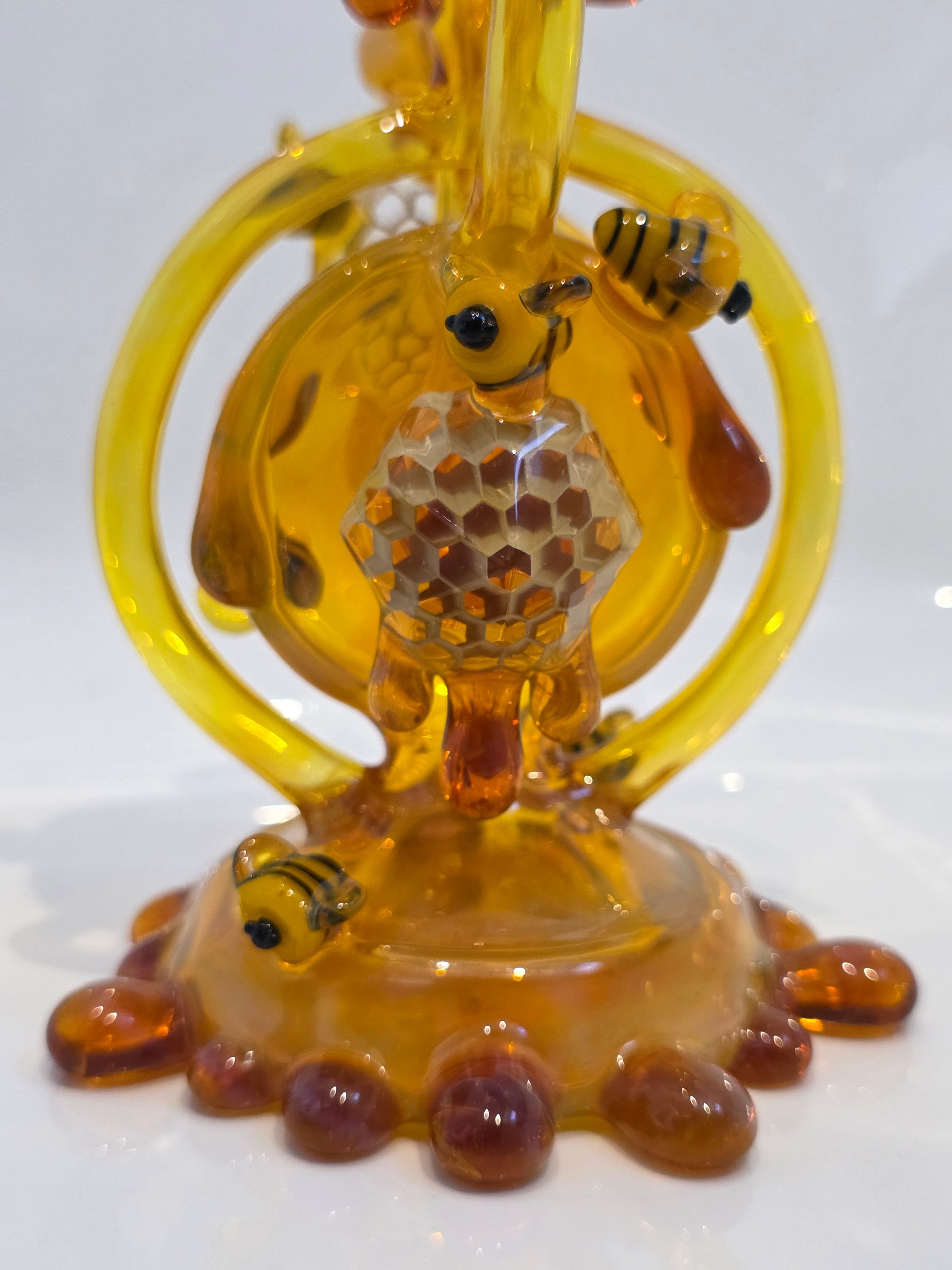 Joe P Glass Rig . A bee themed glass rig with bees and honey dripping on a white background and has a banger attached to it 