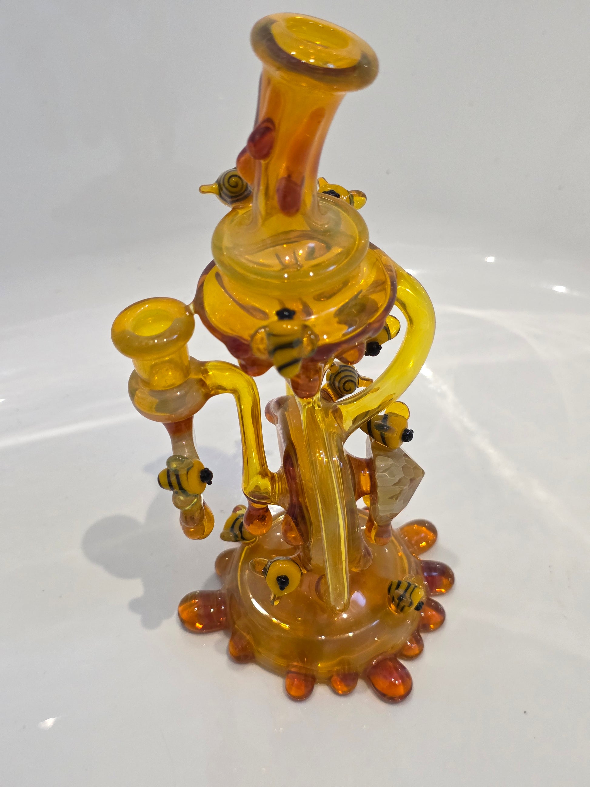 Joe P Glass Rig . A bee themed glass rig with bees and honey dripping on a white background and has a banger attached to it 