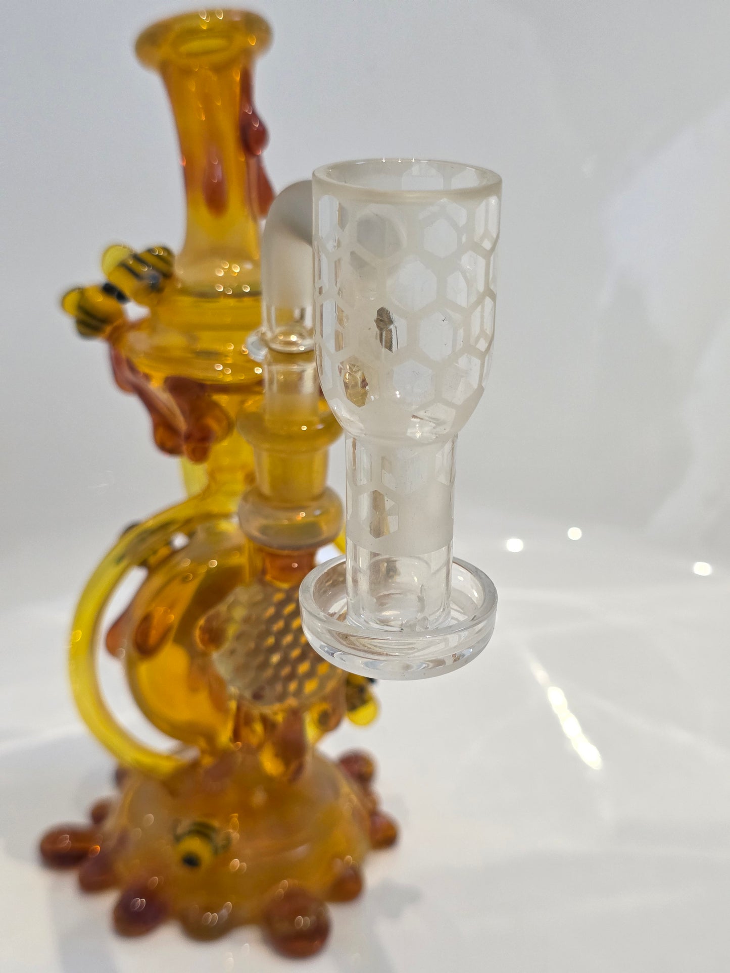 Joe P Glass Rig . A bee themed glass rig with bees and honey dripping on a white background and has a banger attached to it 