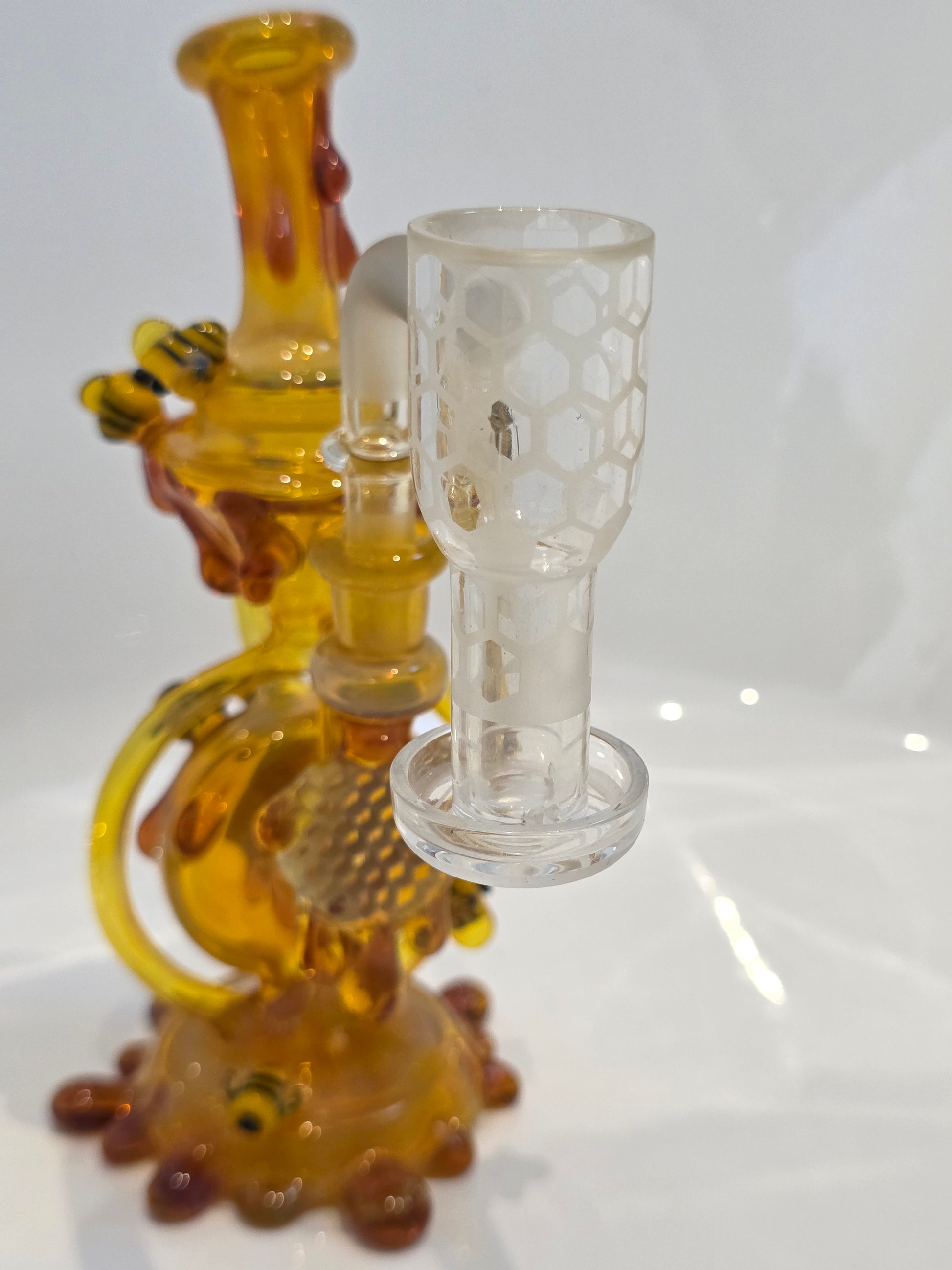 Joe P Glass Rig . A bee themed glass rig with bees and honey dripping on a white background and has a banger attached to it 