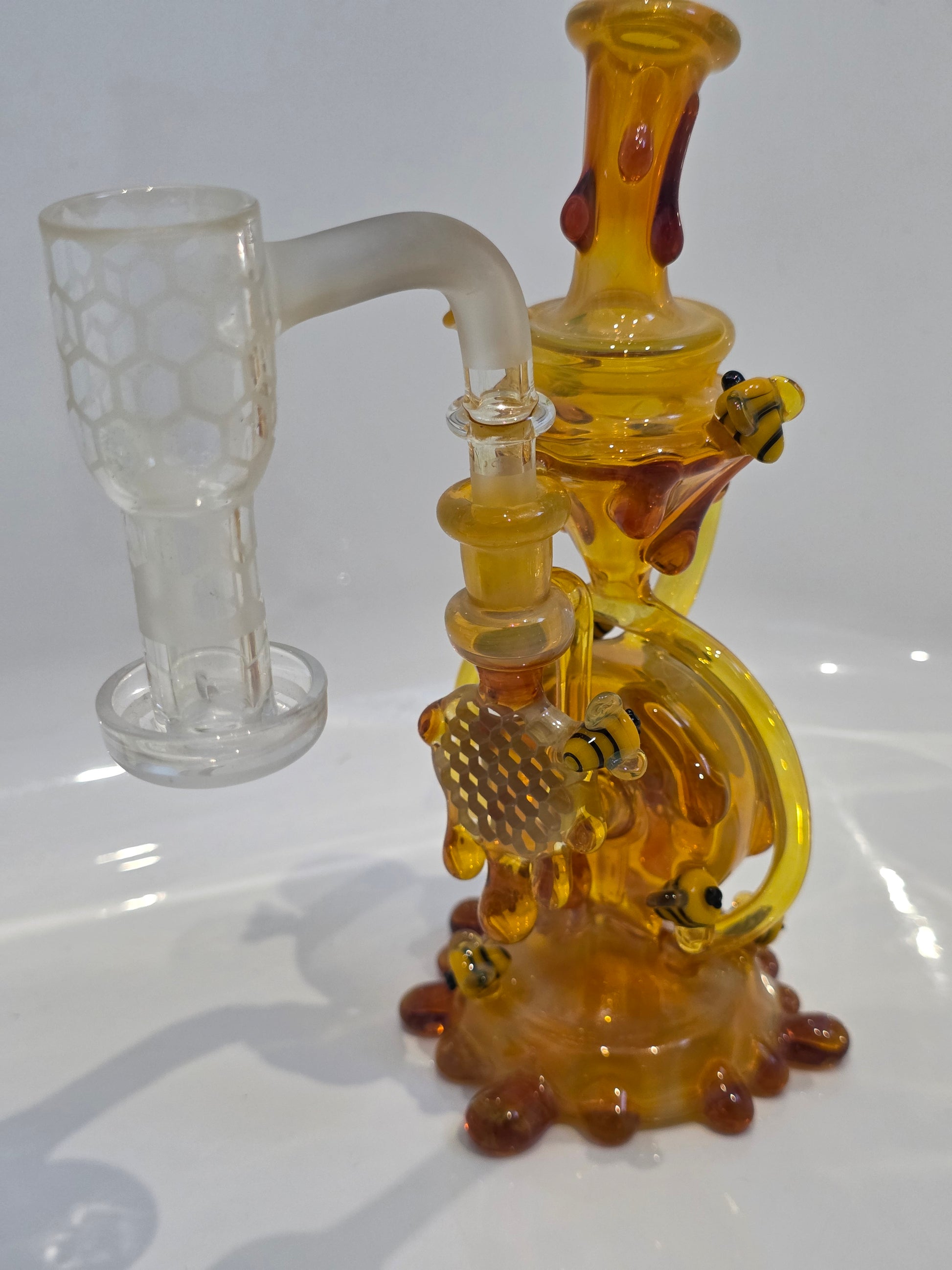 Joe P Glass Rig . A bee themed glass rig with bees and honey dripping on a white background and has a banger attached to it 