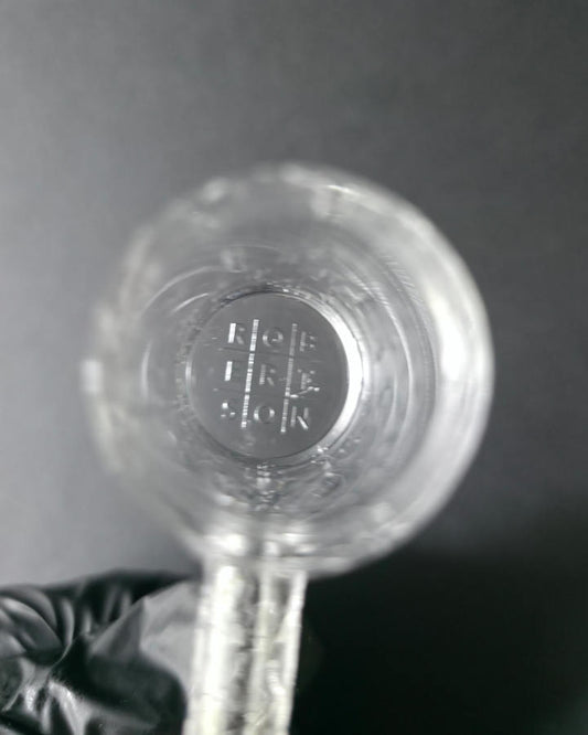 Clear glass quartz banger with embossed design on a dark grey background