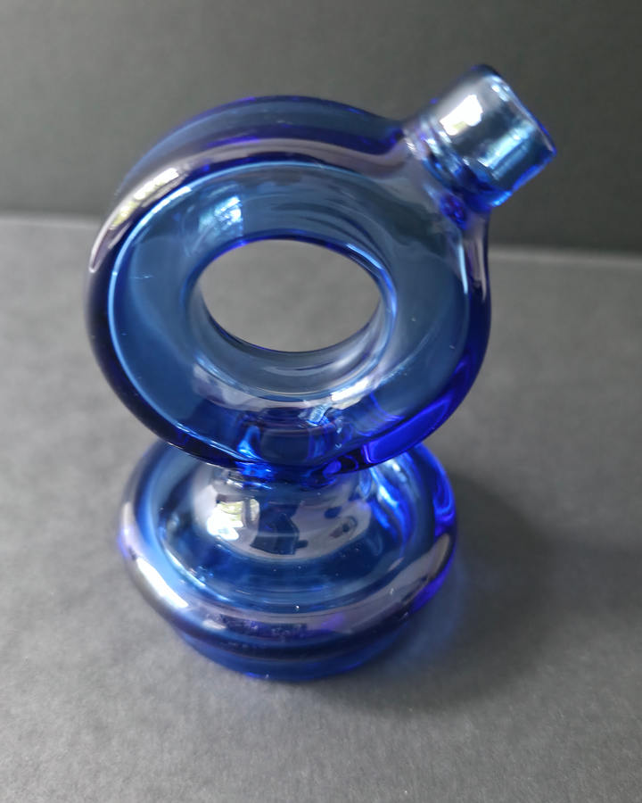 Blue glass puffco topper on a gray surface