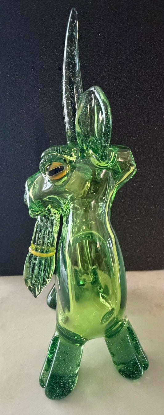 Robertson Glass Green glass goat rig figurine with long horns on a dark background