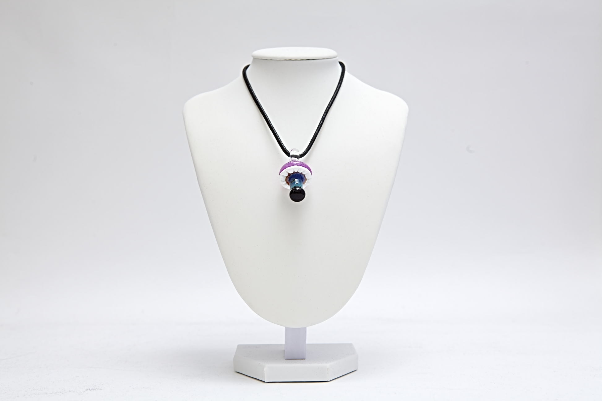 Necklace with a glass mushroom pendant on a white mannequin bust against a white background
