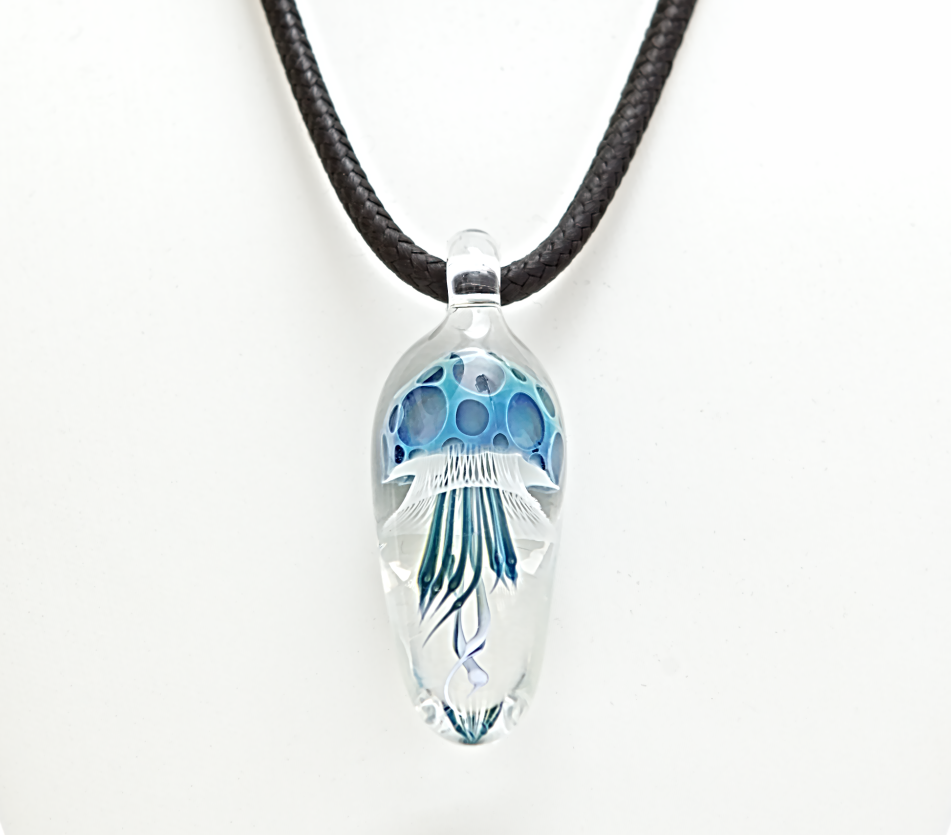 Clear pendant with blue design on a black cord against a white background