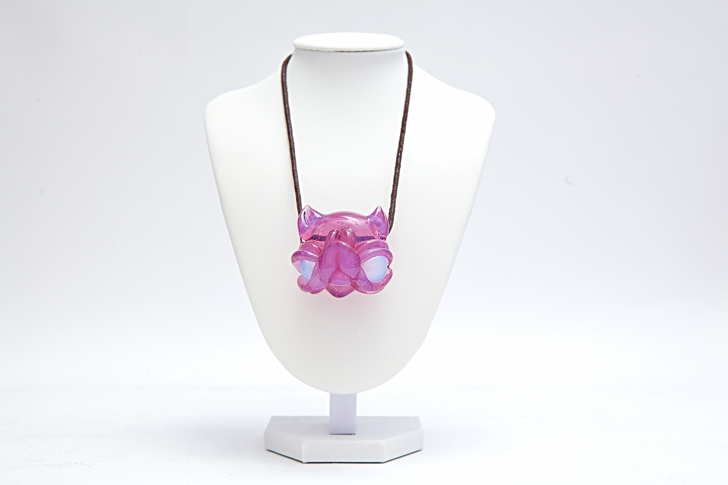 Necklace with a pink pendant on a white mannequin bust against a white background