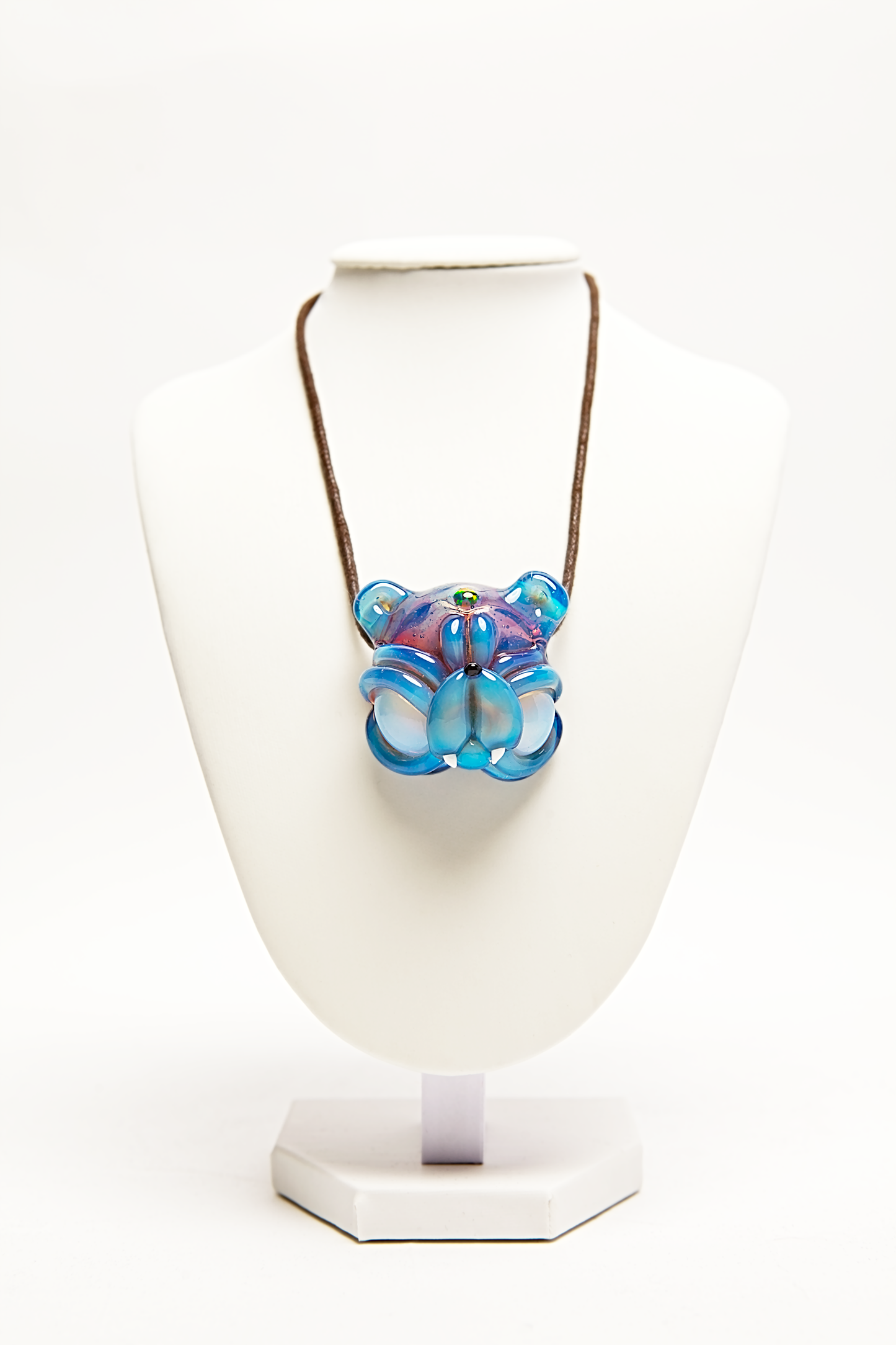 Necklace with a blue and pink pendant on a white stand