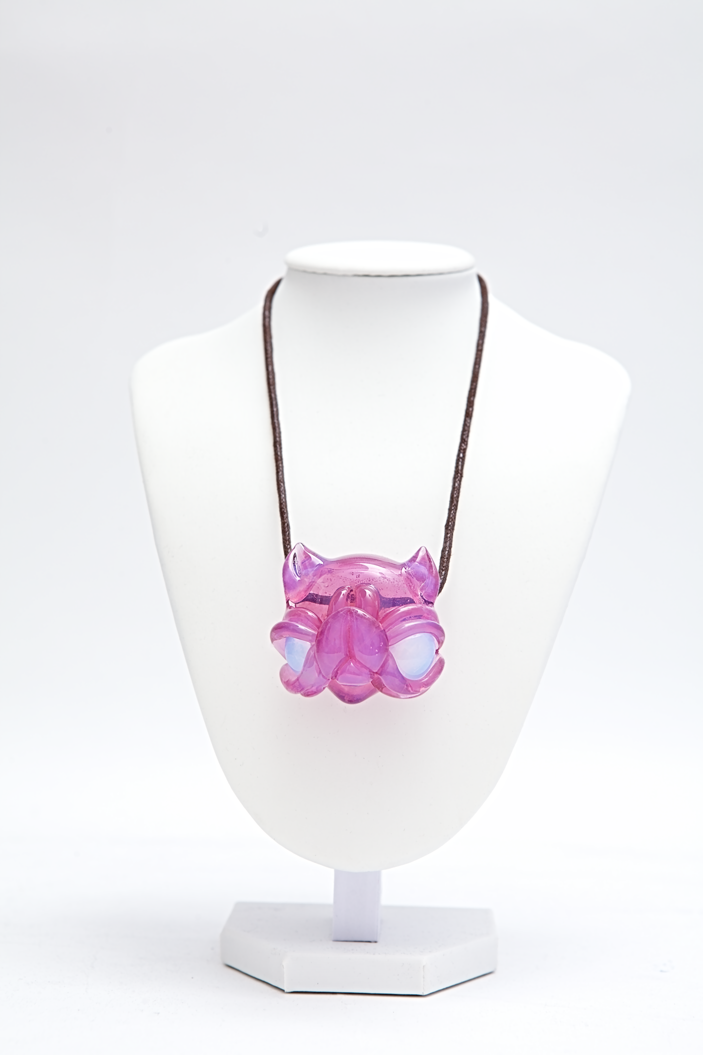 Necklace with a pink and white pendant on a mannequin bust against a white background