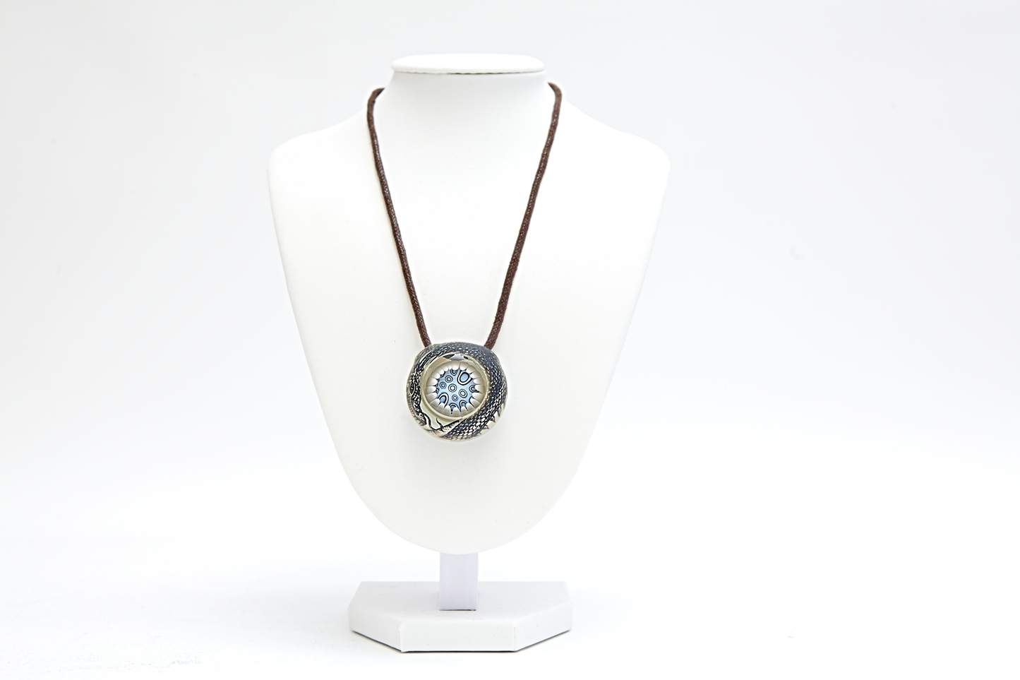Silver pendant with a circular design on a white background