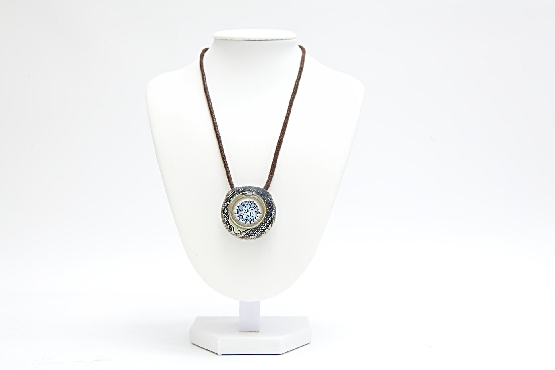 Silver pendant with a circular design on a white background