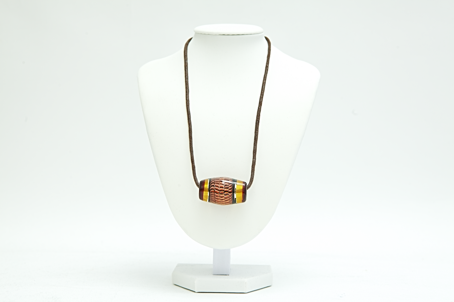 Necklace with a brown cord and multicolored pendant on a white mannequin bust.