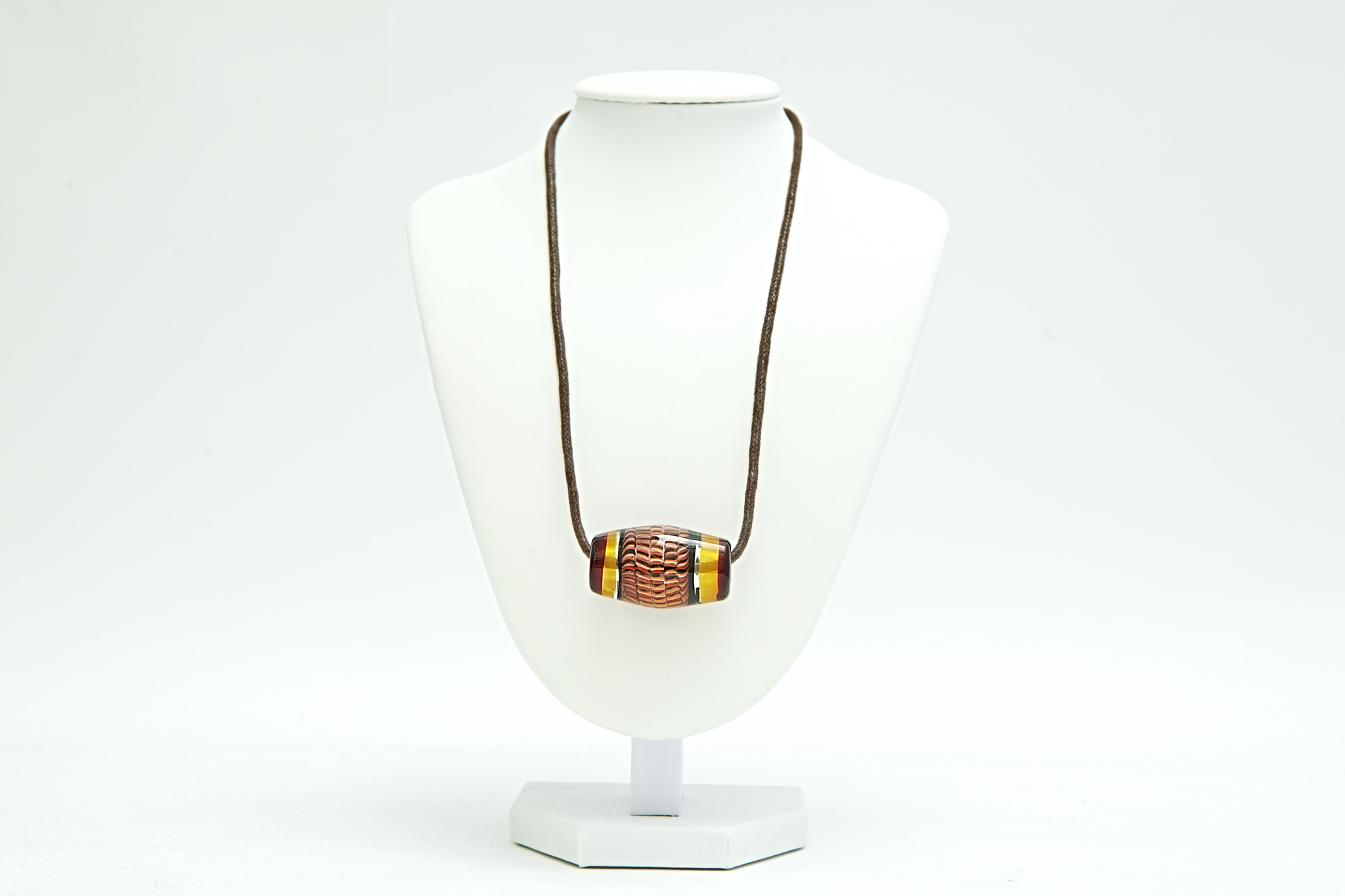 Necklace with a brown cord and multicolored pendant on a white mannequin bust.