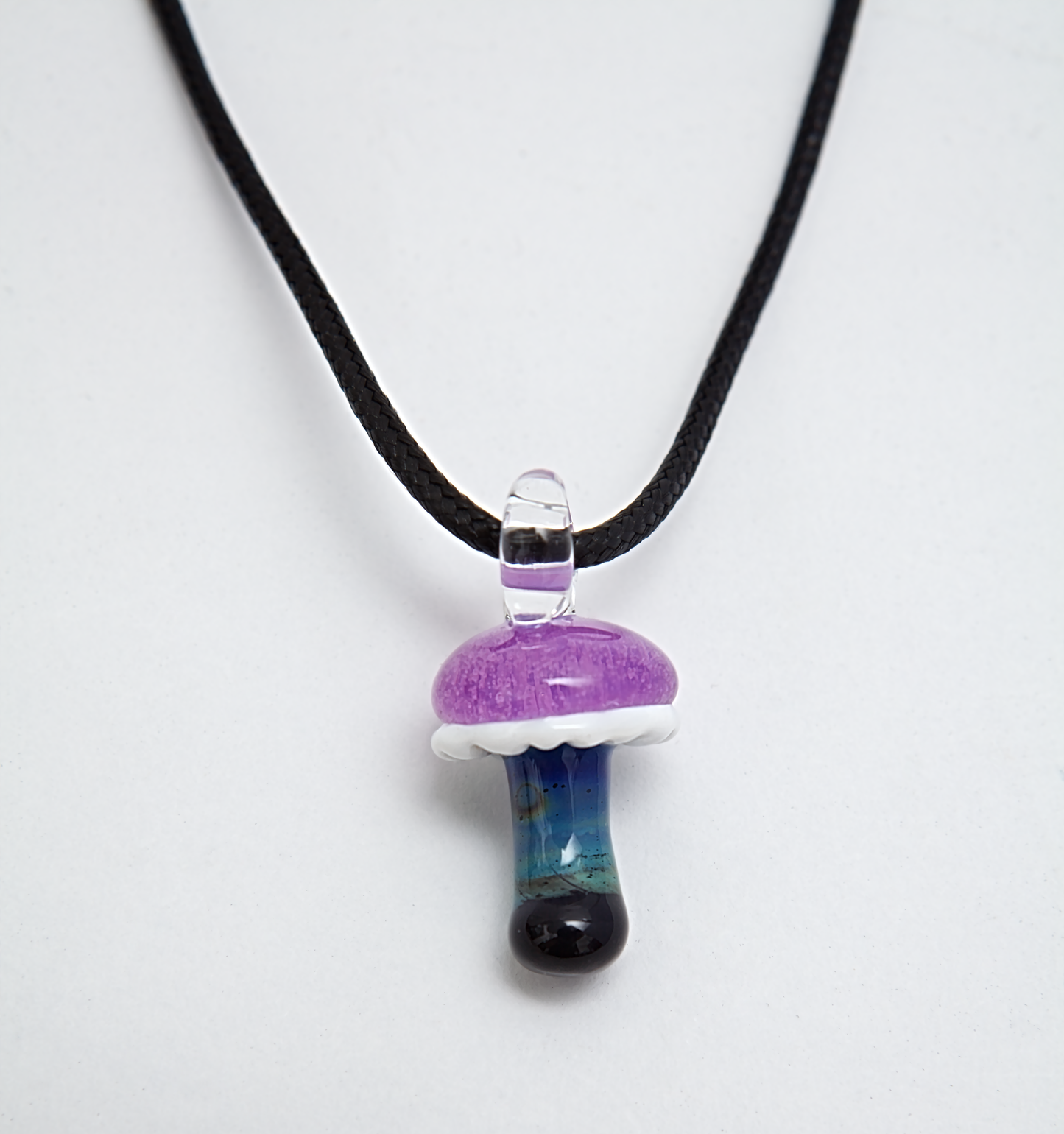 Mushroom-shaped pendant on a black cord against a white background