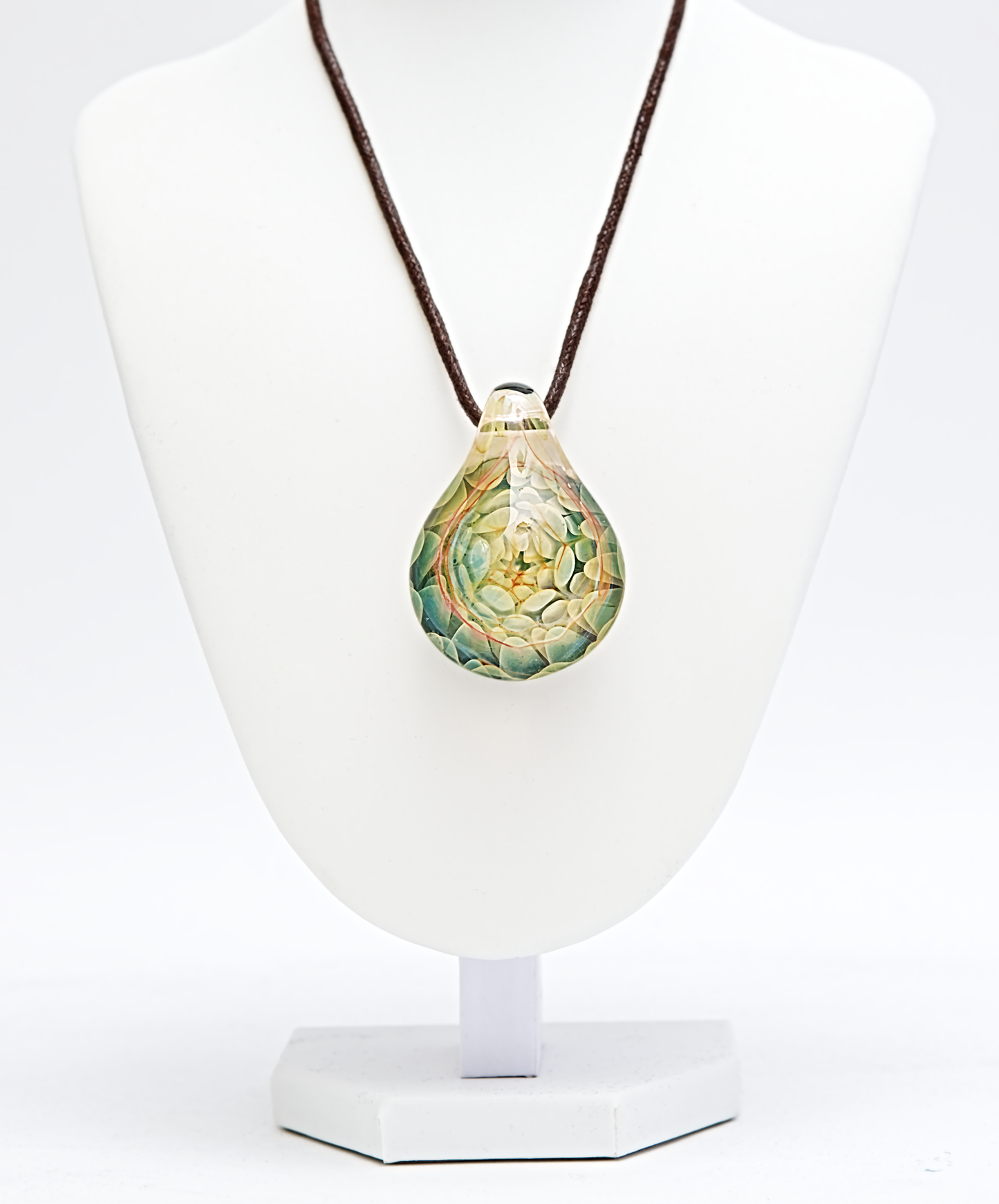 Teardrop-shaped pendant on a brown cord displayed on a white stand with a white background