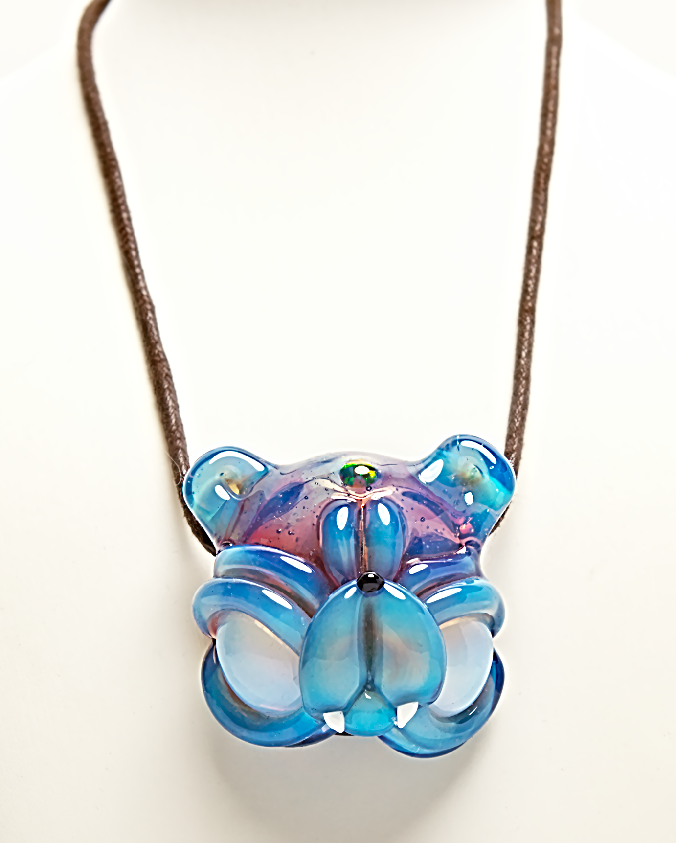 Blue and purple floral pendant on a brown cord against a white background