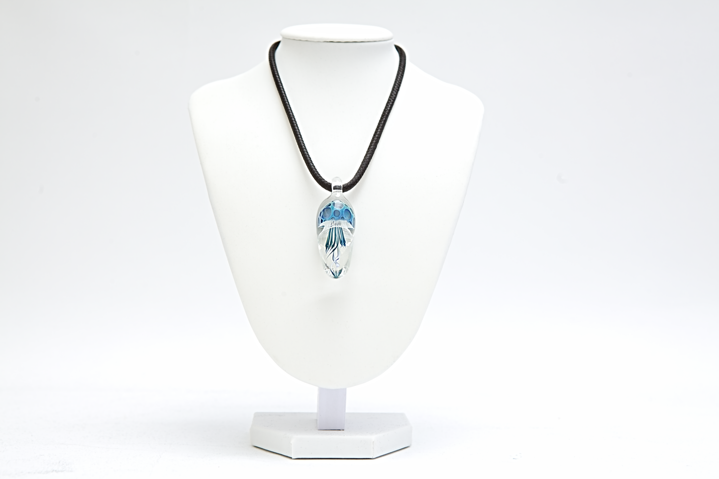 Necklace with a blue pendant on a white mannequin bust against a white background