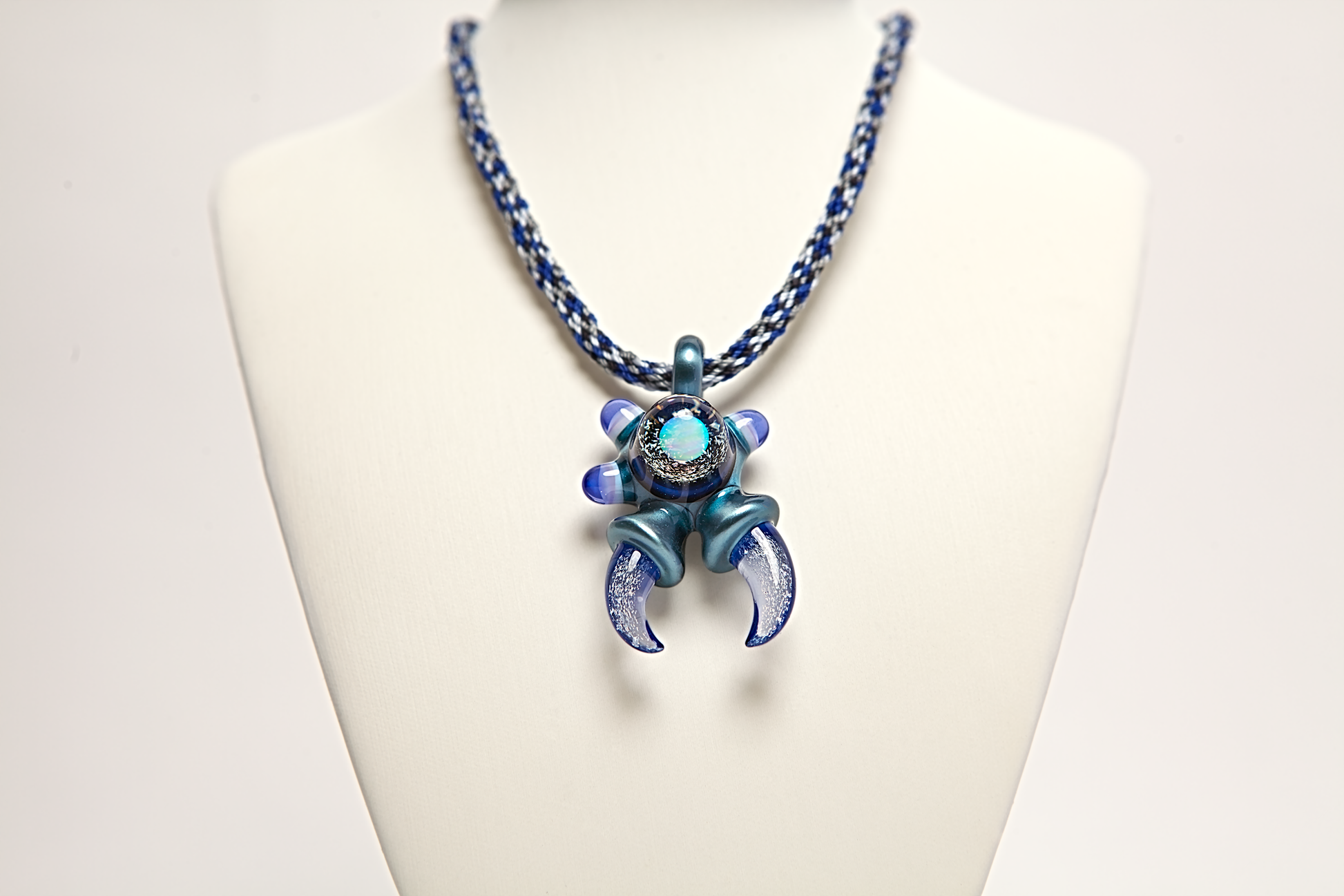 Blue and silver necklace with a unique pendant on a white mannequin bust.