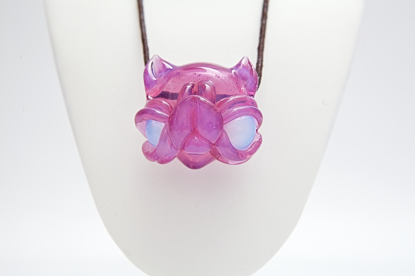 Pink and purple glass pendant on a white stand