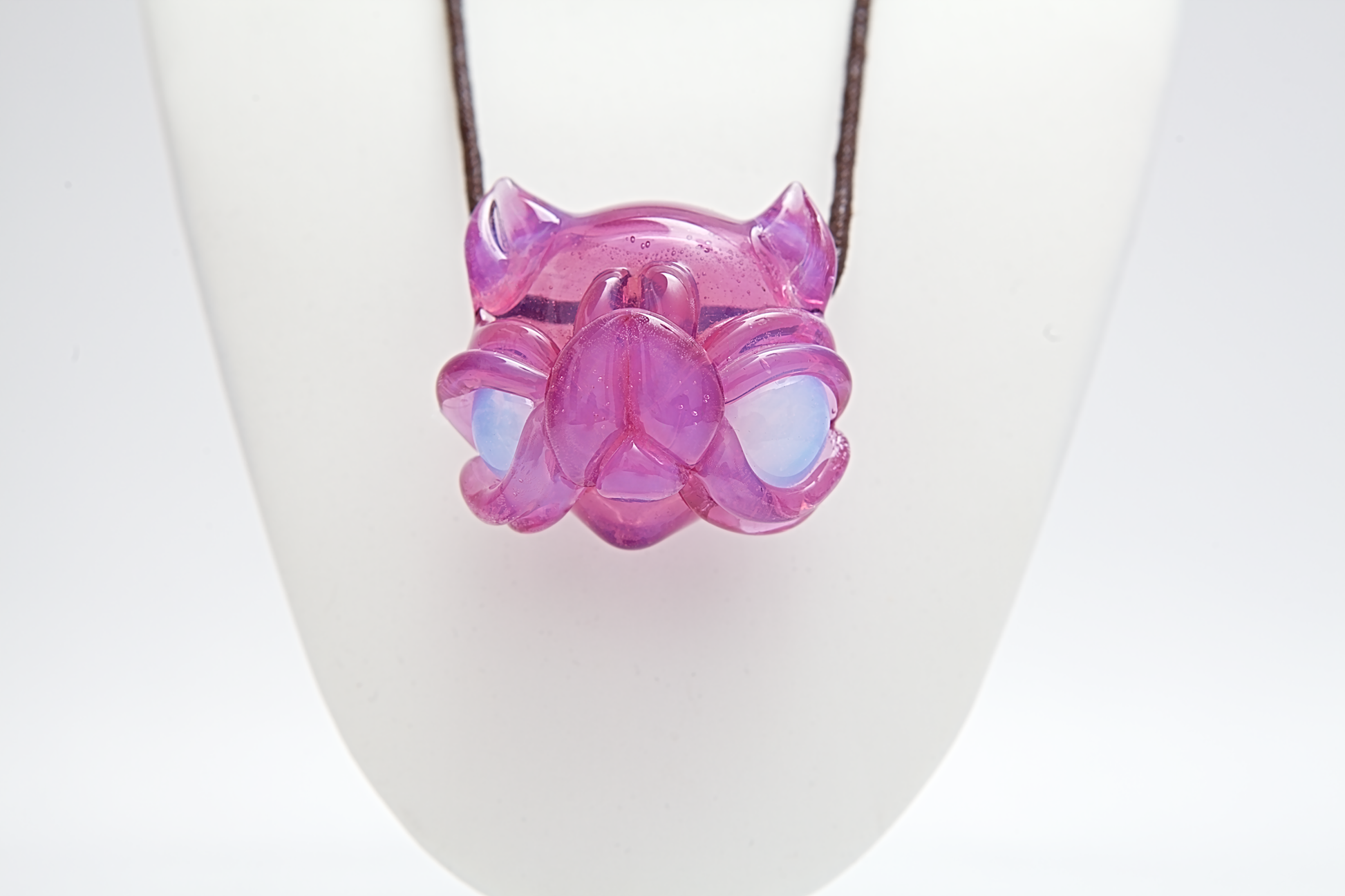 Pink and purple glass pendant on a white stand
