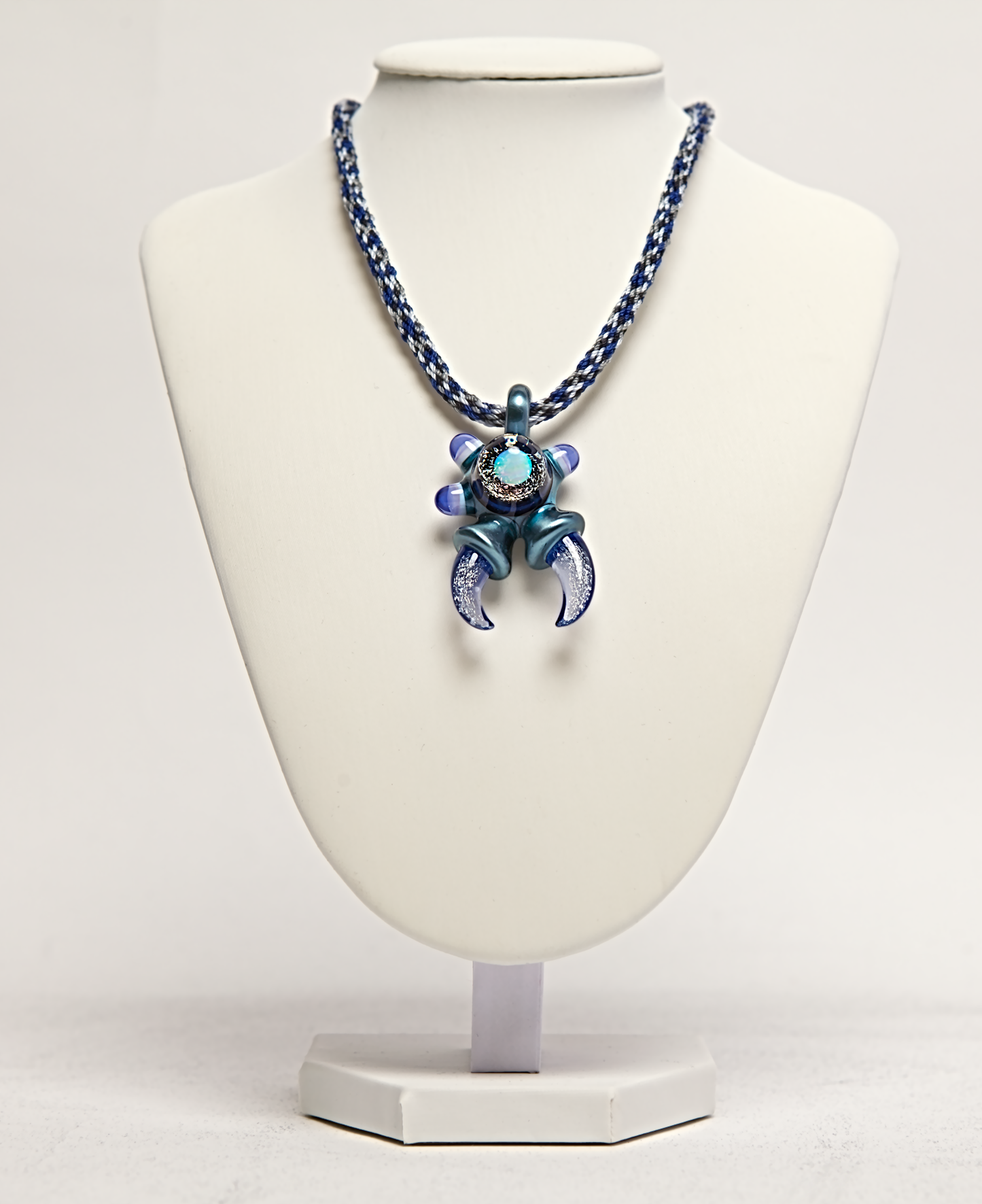 Necklace with a blue and purple pendant on a white mannequin bust.