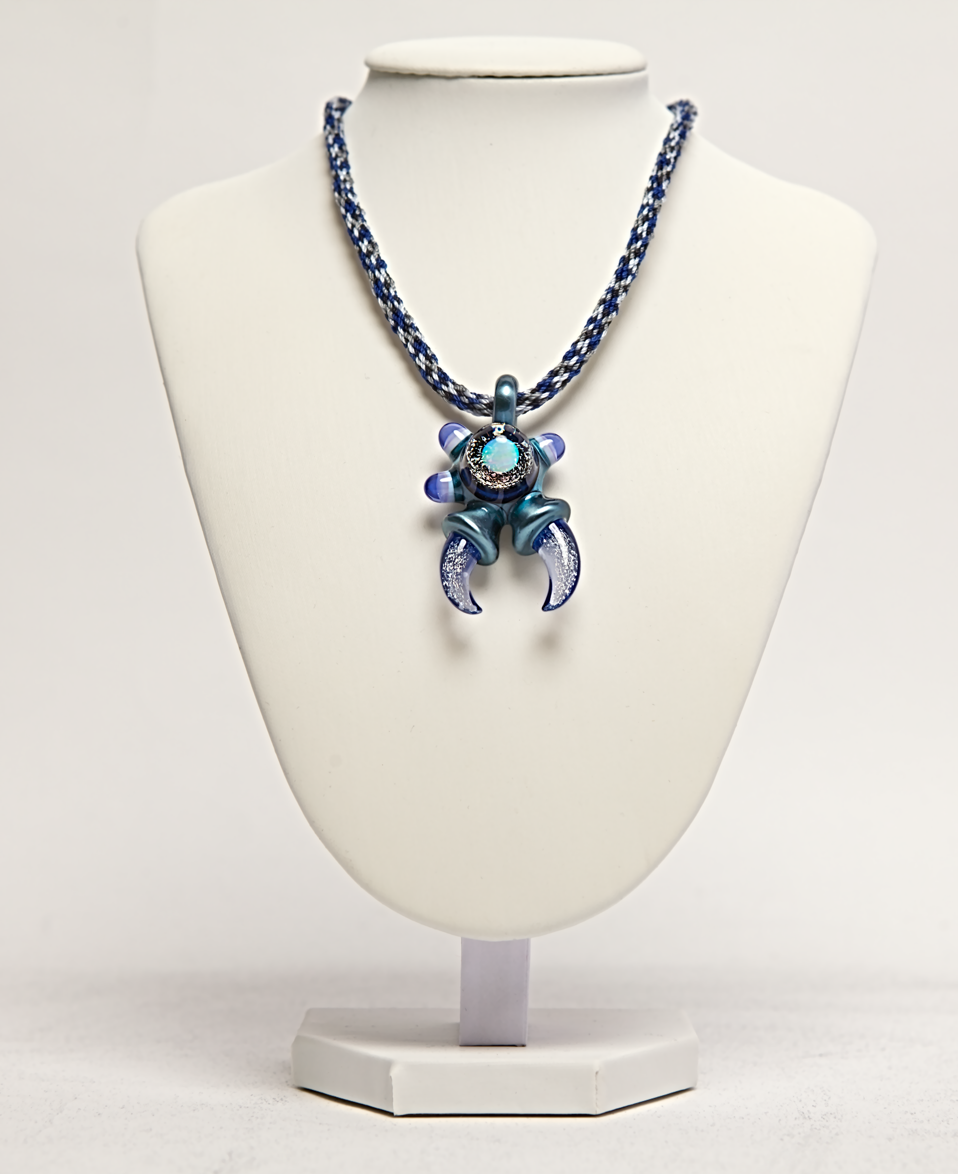 Necklace with a blue and purple pendant on a white mannequin bust.